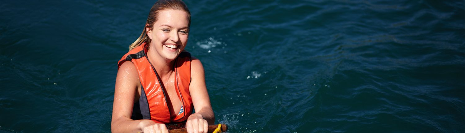Girl in water smiling holding a water ski handle